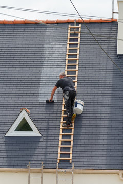 Ouvrier peignant le toit d'une maison