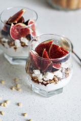 Fresh figs with vanilla whipped cream, cheese, nuts and maple syrup in a glass beaker. Healthy beverage. Healthy food, dieting and breakfast concept. Freshly made yoghurt with seeds and fruits