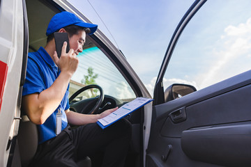 Delivery man sitting on van seat and calling to customer.Delivery service concept