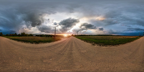 full seamless spherical panorama 360 degrees angle view on gravel road among fields in evening sunset with awesome clouds before the storm in equirectangular projection, VR AR virtual reality content
