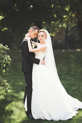 Lovely happy wedding couple, bride with long white dress posing in beautiful city