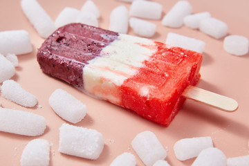 Fruit berry appetizing ice lolly with ice slices on a pink background.