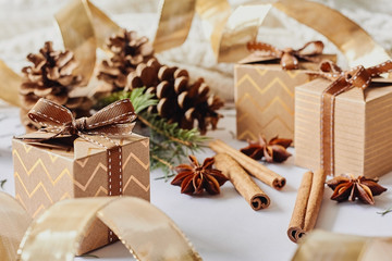 Christmas and New Year holidays concept. Gift boxes with ribbon, fir branch, cones, cinnamon, anise on white knitted background