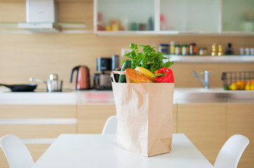 Paper shopping bag full with groceries products on kitchen table