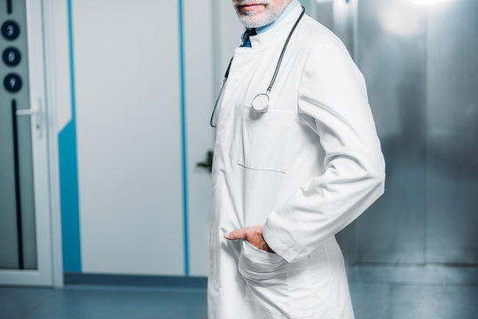 cropped image of male doctor with stethoscope over neck posing in hospital corridor