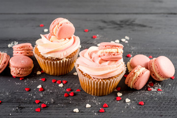 Sweet cupcakes with macaroons on the wooden background