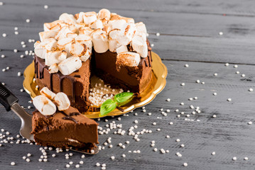 A chocolate cake with marshmallows on the wooden background