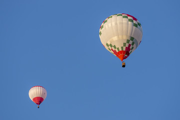 Pair of hot-air balloons lit by the light of the sunset against a beautiful blue sky