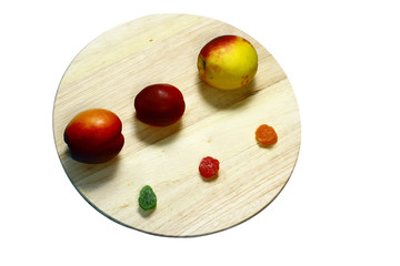 Still life of three fresh peaches on a round board.