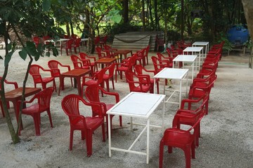 Fototapeta na wymiar Outdoor jungle cafe with red chairs and white tables in Southeast Asia