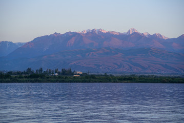 View of the lake and mountains during sunset, which creates purple shadows.