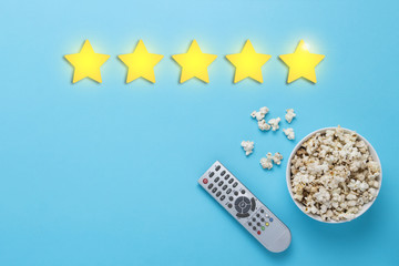 Bowl of popcorn and a remote from the TV set on a blue backgroun
