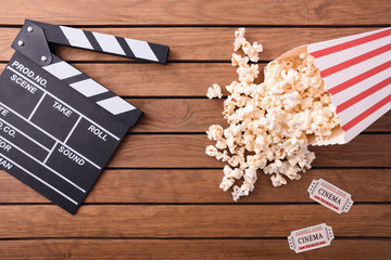 Obraz premium Popcorn tickets and clapperboard on wooden table