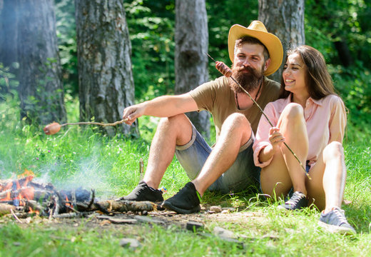 Hike picnic traditional roasted food. Camping and picnic. Hipster and girl roasting sausages. Couple in love camping forest roasting sausage. Couple prepare roasted sausages snack nature background