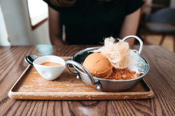 A woman with Thai tea ice cream and cotton candy with syrup in cafe