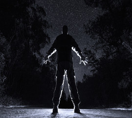 Man and the Universe concept: majestic silhouette of a man photographed at the lowest point on the background of countless stars. Confrontation of a small man against a vast world.