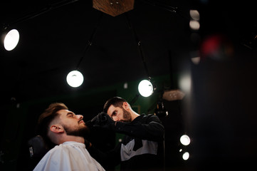 Handsome bearded man at the barbershop, barber at work.