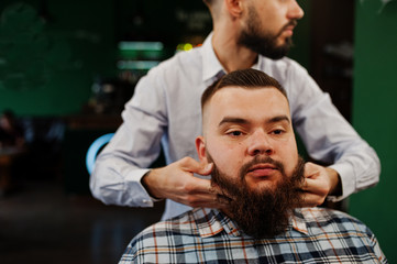 Handsome bearded man at the barbershop, barber at work.