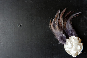 Brooch, as an ornament from a flower and feathers on a black board