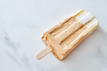 Coffee and chocolate popsicle against a marble background with copy space