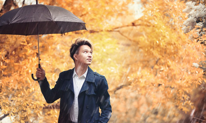 Autumn rainy weather and a young man with an umbrella