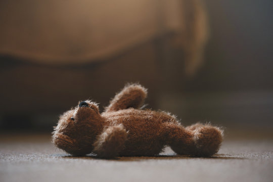 Teddy bear is laying down on carpet in retro filter, Lonely teddy bear laying down alone in living room at night ,lonely concept, international missing children's day.