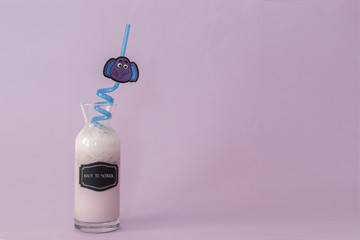Strawberry milk/ Milkshake in jar, back to school overwritten, with purple elephant pink pipette, on purple background and with writing space