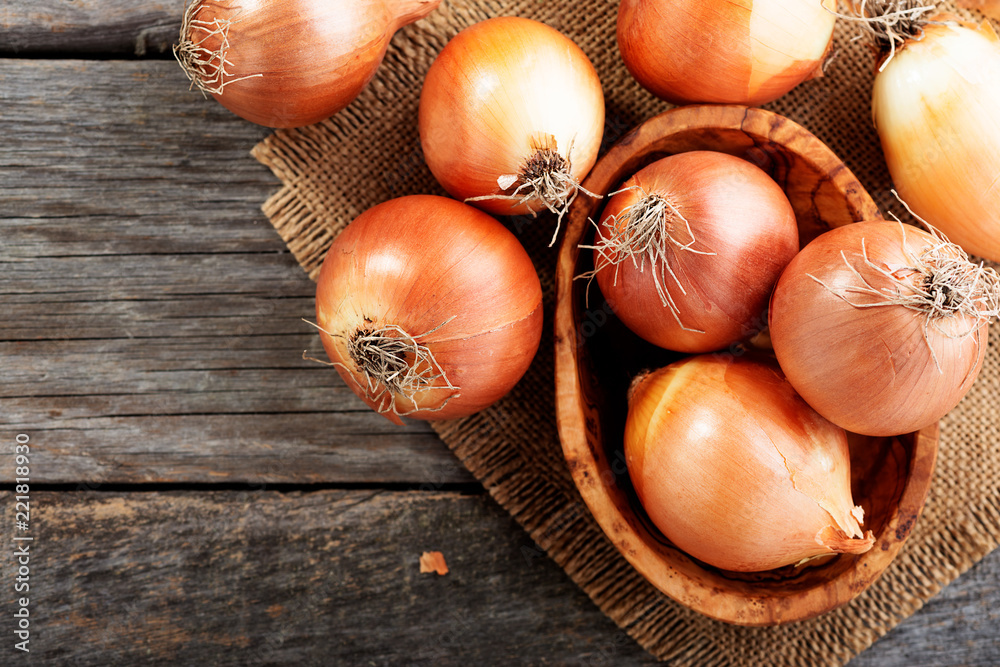 Wall mural fresh raw onions on wooden background. top view.