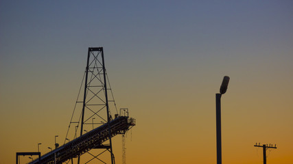 Conveyor belt carrying ore at a mine site processing plant. Sunset industrial landscape. Cobar, NSW, Australia