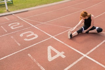Female athletic exercising on running track