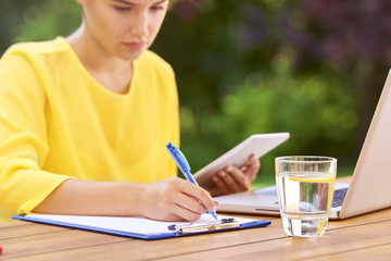 Happy young woman learning at home and using laptop outdoors at garden