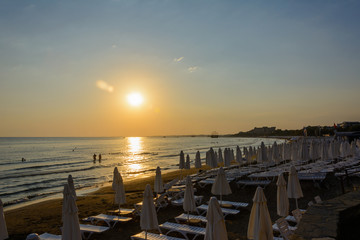 Obraz premium empty sea beach at sunset. folded umbrellas. boats on the horizon