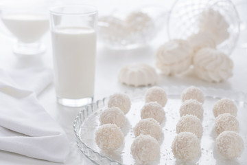 coconut candy and a glass of milk on a white background. concept: sweet breakfast