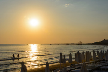 empty sea beach at sunset. folded umbrellas. boats on the horizon. vanilla tones