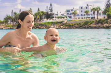 Mom teaches a little son to swim in the sea