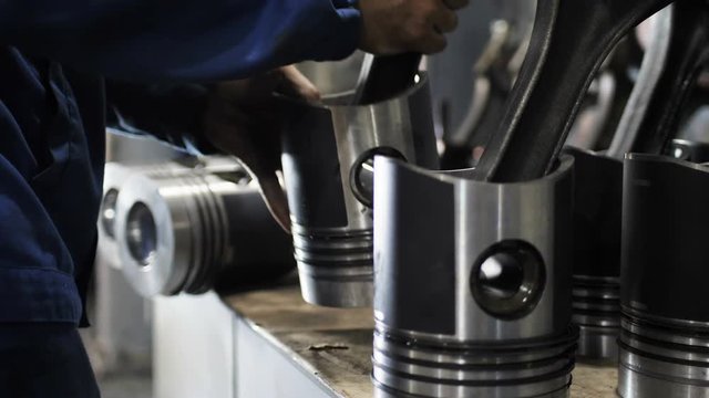 technician puts KAMAZ lorry pistons in line on desk