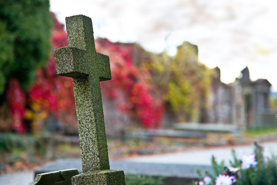 Old cross on graveyard in the autumn