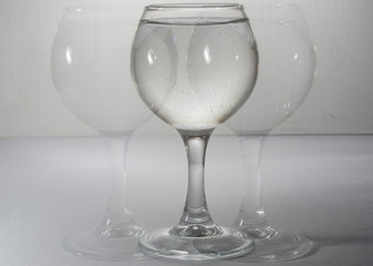 A glass with water in different light and with its own copies like a shadow