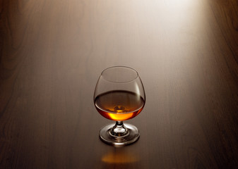 view of glass of  cognac on brown color wooden table surface