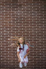 Happy cute schoolgirl jumping in a street
