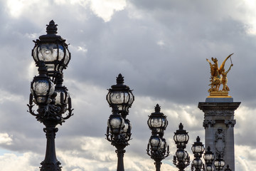 Fototapeta na wymiar Lanterns on the Pont Alexandre III against a cloudy sky in Paris 