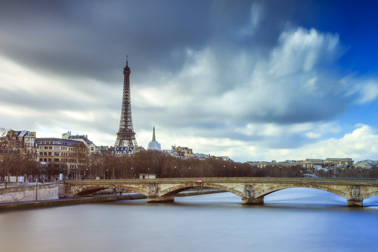 Beautiful long exposure view of the river Seine in Paris, with the Eiffel tower in the background, on a cloudy winter day 