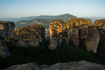 Fototapeta na wymiar Huge rocks with christian orthodox monasteries at sunrise with Meteora valley in background near Kalambaka, Thessaly, Greece