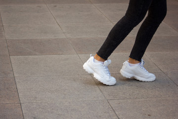 A girl wearing white sport sneakers on outdoor