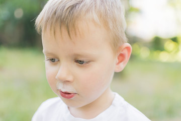 The little boy smeared his face with a white drink.