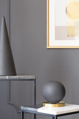 Black ball and cone on table against grey wall with poster in museum interior. Real photo