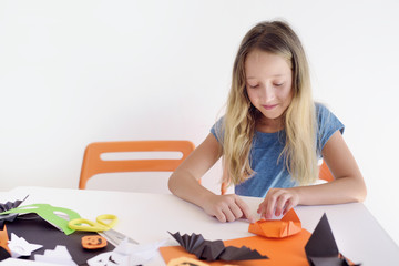  The girl at a table puts origami from paper. Preparation for a holiday