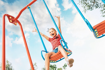 Happy smiling cute little girl have fun when swing on swing