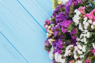 Bouquet of limonium flowers on wood, close up. Copyspace, free space for text. Blue wooden table background.