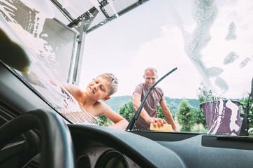 Boy helps his father with car washing